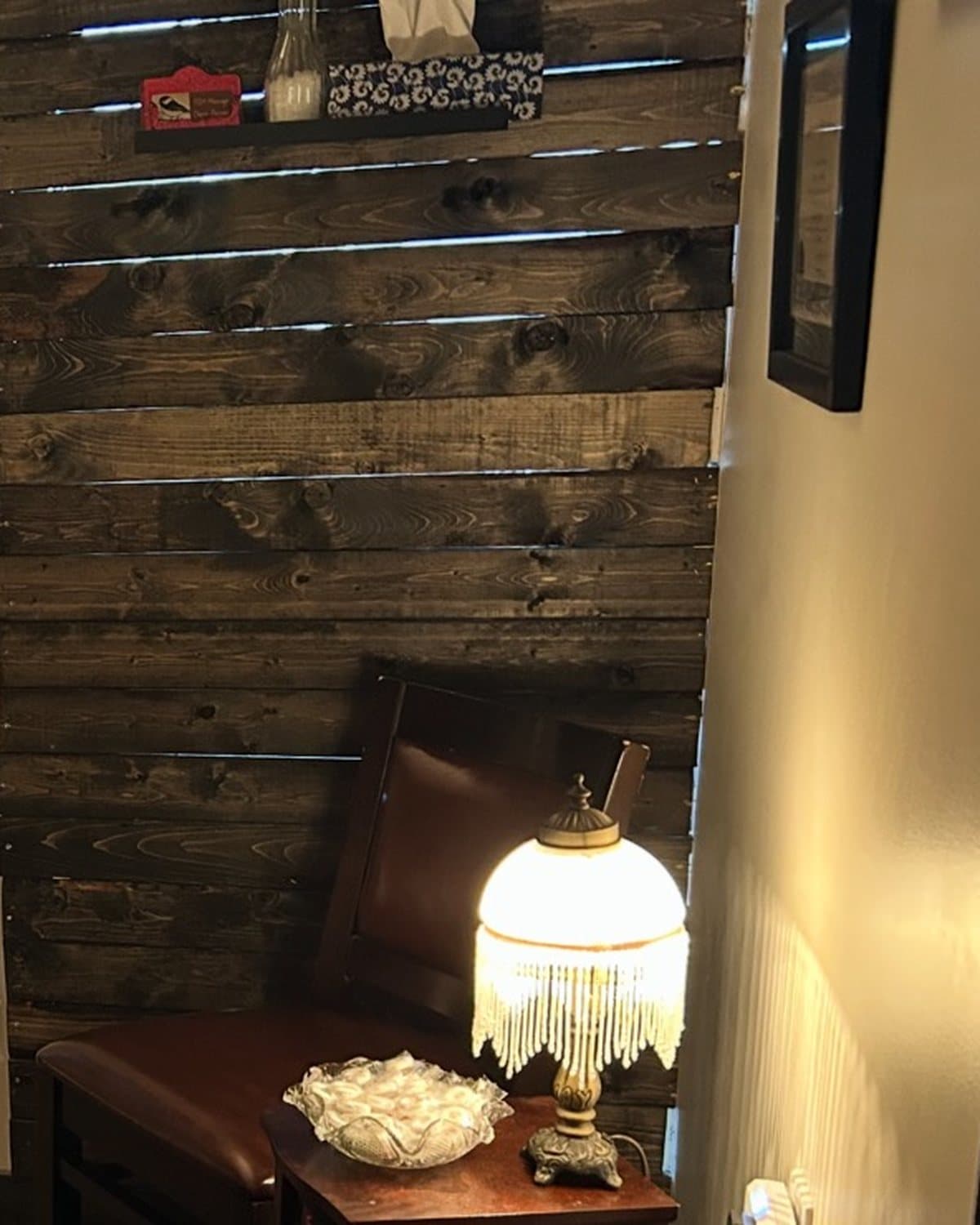 Wood feature wall, chair and a glowing lamp in a treatment room at TCH Massage in Olds