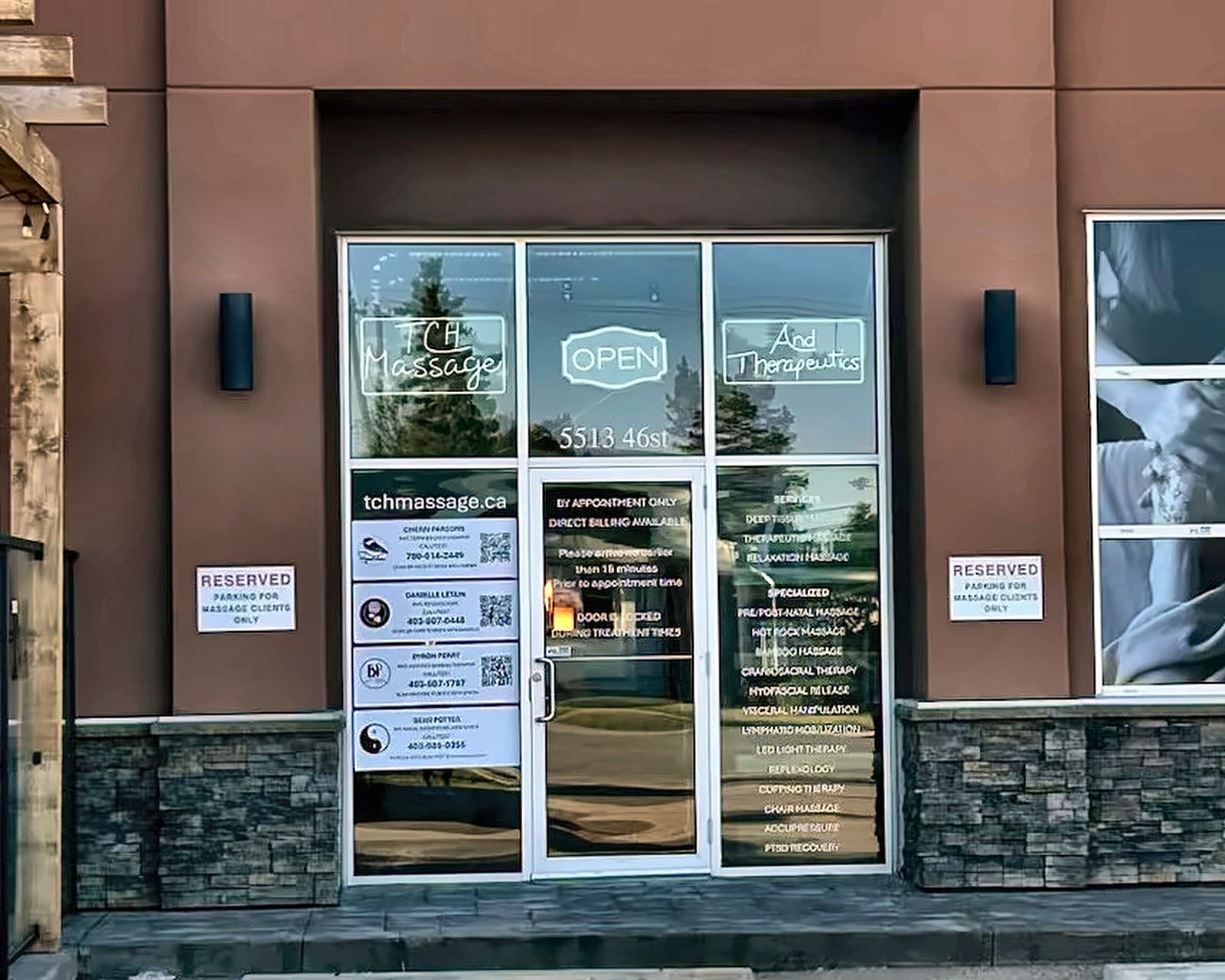 The front of TCH Massage & Therapeutics at 5513 46 Street in Olds, with the neon signs lit in the windows